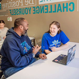 Students smiling with laptop in front of them