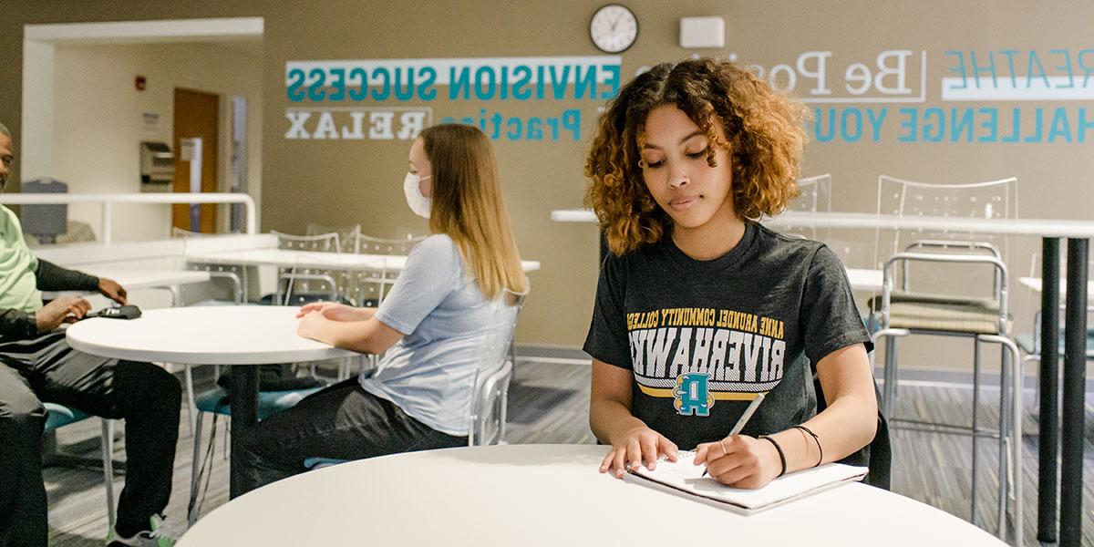 Female student in writing in notebook in study room